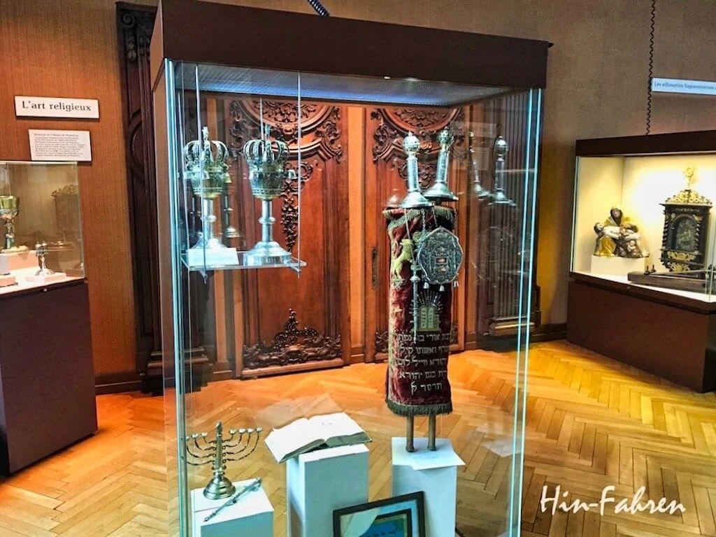 Torahrolle, siebenarmiger Leuchter und im Hintergrund Meßkelch und Pieta im Museum Haguenau