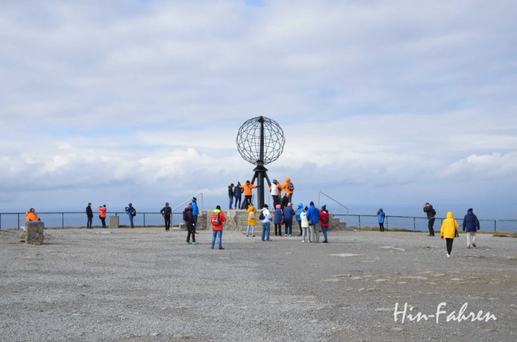 Eine Reisegruppe in bunten Jacken rund um den Globus am Nordkap