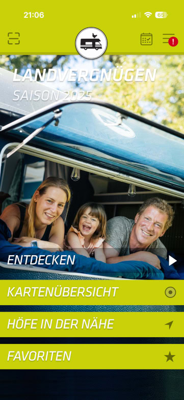 Eine lächelnde Familie - Mutter, Vater und kleines Kind - liegt auf dem Rücksitz eines Wohnmobils mit offener Luke und genießt einen Moment im Freien. Die App-Oberfläche bietet Optionen auf Deutsch, darunter Entdecken und Favoriten.