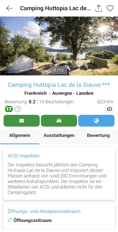 An einem sonnigen Tag sind mehrere Zelte auf einer Wiese unter Bäumen neben einem See und Bergen aufgebaut. Die Leute entspannen sich in der Nähe der Zelte. Dies ist ein Eintrag für Camping Huttopia Lac de la Siauve in Auvergne, Frankreich.
