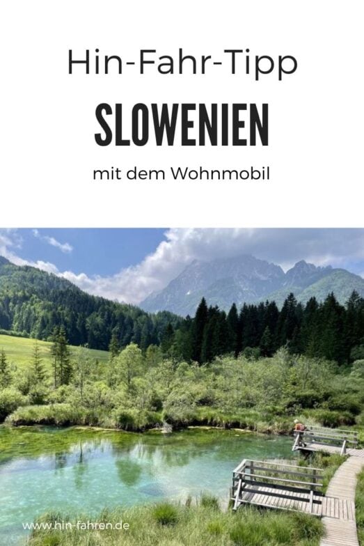 Ein Holzsteg führt über einen türkisfarbenen See inmitten üppiger Waldlandschaft und mit Blick auf die Berge. Der deutsche Text lautet: Hin-Fahr-Tipp – Slowenien mit dem Wohnmobil. Perfekt für ein malerisches Abenteuer in Slowenien mit dem Wohnmobil.