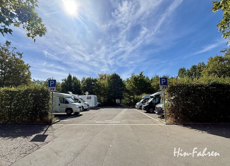 Ein Wohnmobilstellplatz an der Hohenzollernstraße, umgeben von Bäumen und Hecken, mit blauen Parkschildern.