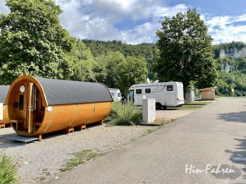 Eine tonnenförmige Holzhütte, die zur Vermietung steht und neben einem Wohnmobil auf einem Campingplatz in der Hohenzollernstraße steht.
